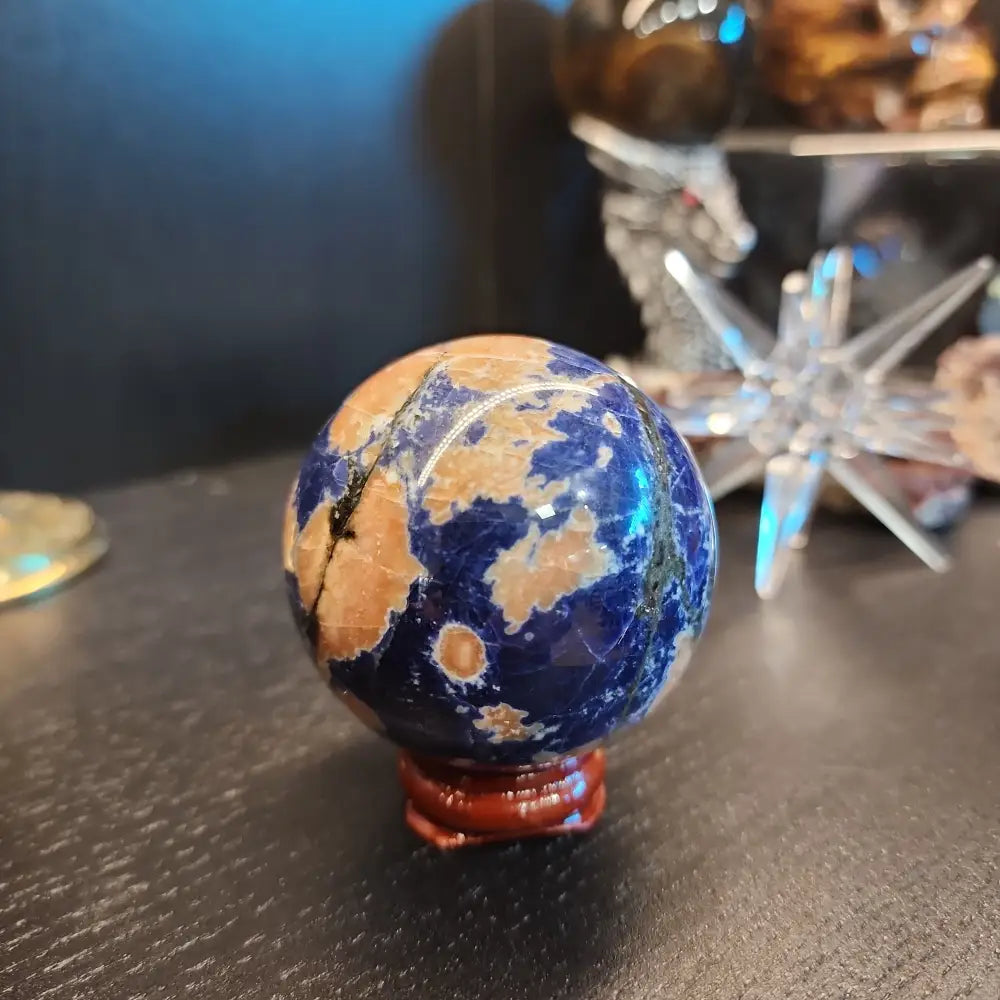 Hand-polished Sunset Sodalite sphere featuring vibrant blue sodalite with glowing orange sunstone streaks, displayed on a white background.