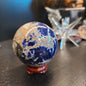 Hand-polished Sunset Sodalite sphere featuring vibrant blue sodalite with glowing orange sunstone streaks, displayed on a white background.
