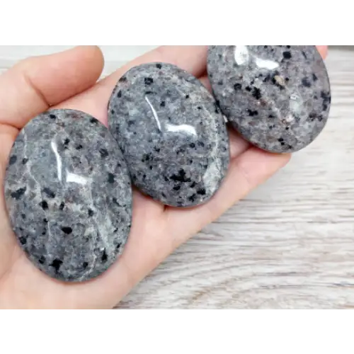 Hand-polished Yooperlite palmstone, glowing with vibrant orange and yellow patterns under UV light, displayed on a white background. Perfect for creativity, transformation, and mystical energy.